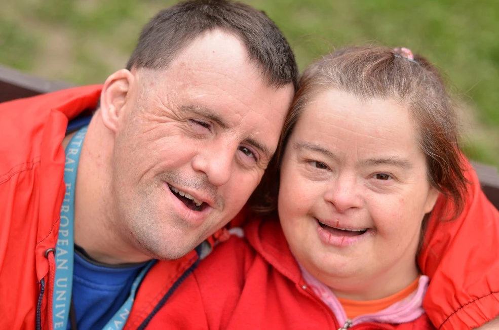 Two disabled friends outside both smiling at camera